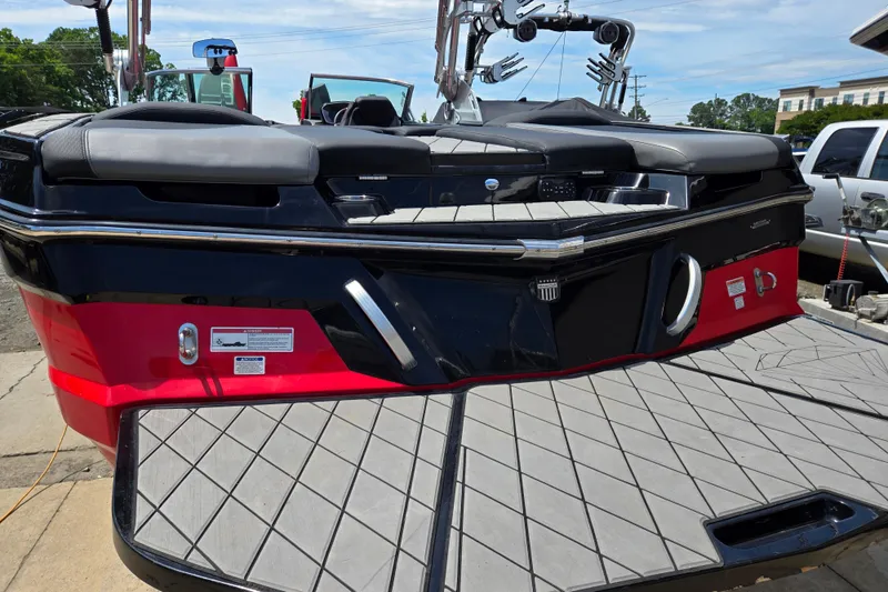 Slide: The Image of 2019 MasterCraft XT25 boat rear view with red and black design, featuring a spacious swim platform. - 21
