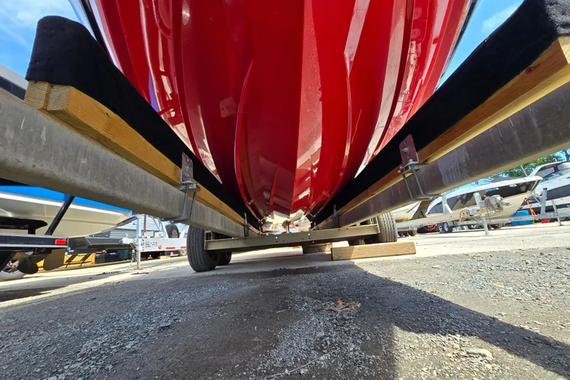 Slide: The Image of Underneath view of a red 2019 MasterCraft XT25 boat on a trailer. - 23