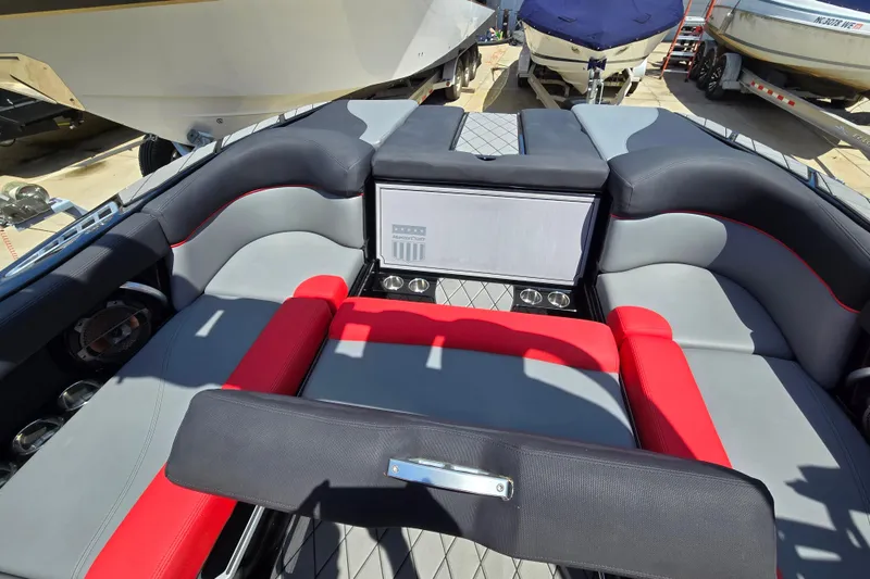 Slide: The Image of 2019 MasterCraft XT25 boat interior with red and gray seating, cup holders, and sleek design. - 26