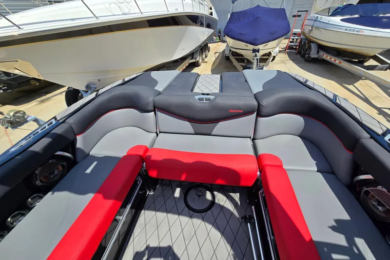 Slide: The Image of 2019 MasterCraft XT25 boat interior with gray and red seating, docked among other boats. - 27