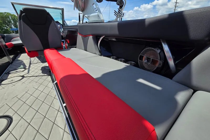 Slide: The Image of 2019 MasterCraft XT25 interior with red and gray seating, speaker, and cup holders. - 29