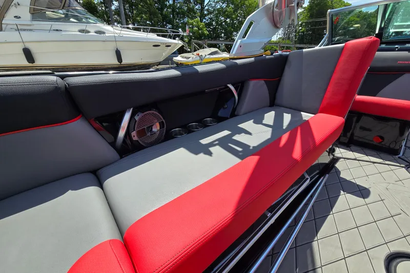 Slide: The Image of 2019 MasterCraft XT25 boat interior with red and gray seating, docked near other boats. - 33