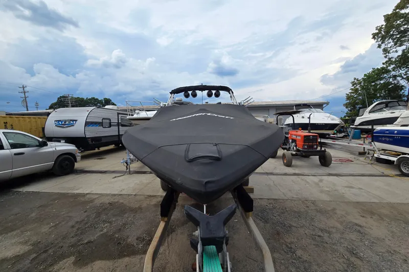Slide: The Image of 2019 MasterCraft XT25 boat covered and parked in a marina with trailers and vehicles. - 4