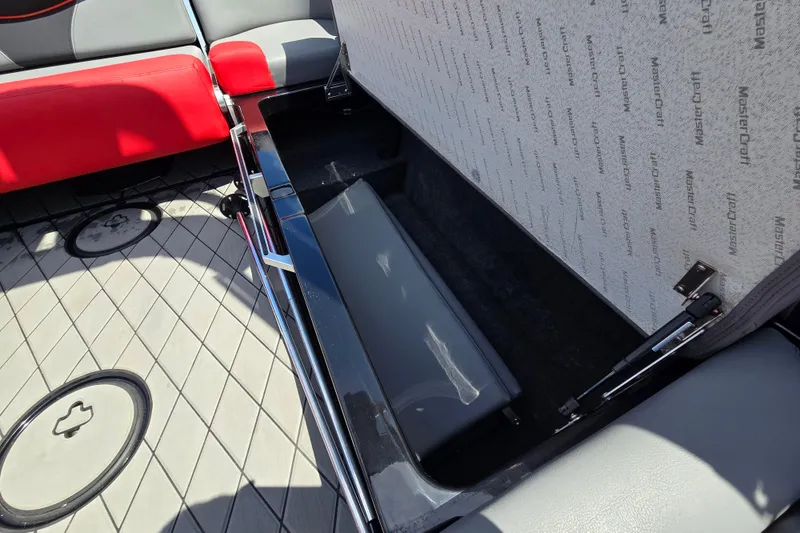 Slide: The Image of 2019 MasterCraft XT25 boat interior storage compartment with red and gray seating. - 43
