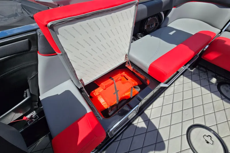 Slide: The Image of 2019 MasterCraft XT25 boat interior with red and gray seating, open storage compartment. - 44
