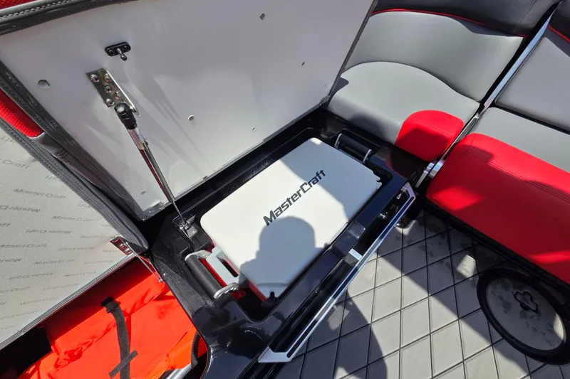 Slide: The Image of 2019 MasterCraft XT25 boat interior storage compartment with red and gray seating. - 45