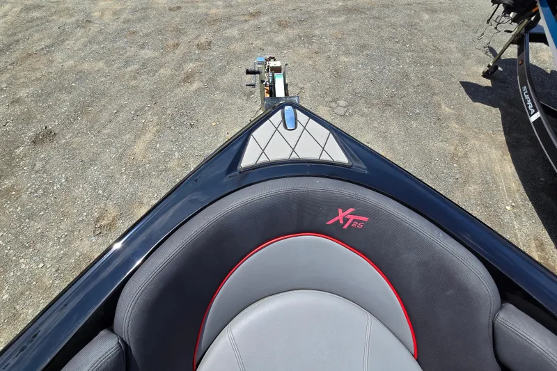 Slide: The Image of 2019 MasterCraft XT25 boat interior with gray and red seating on a gravel surface. - 52
