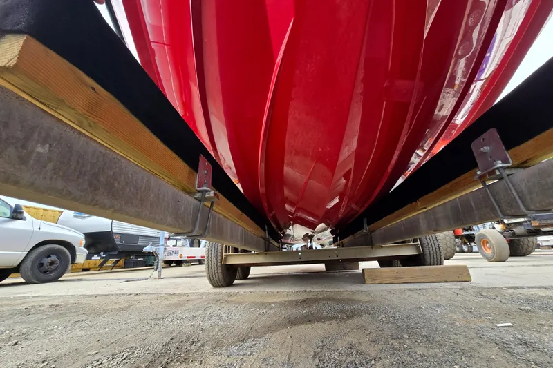 Slide: The Image of Red 2019 MasterCraft XT25 boat hull on trailer, viewed from below in a storage area. - 6