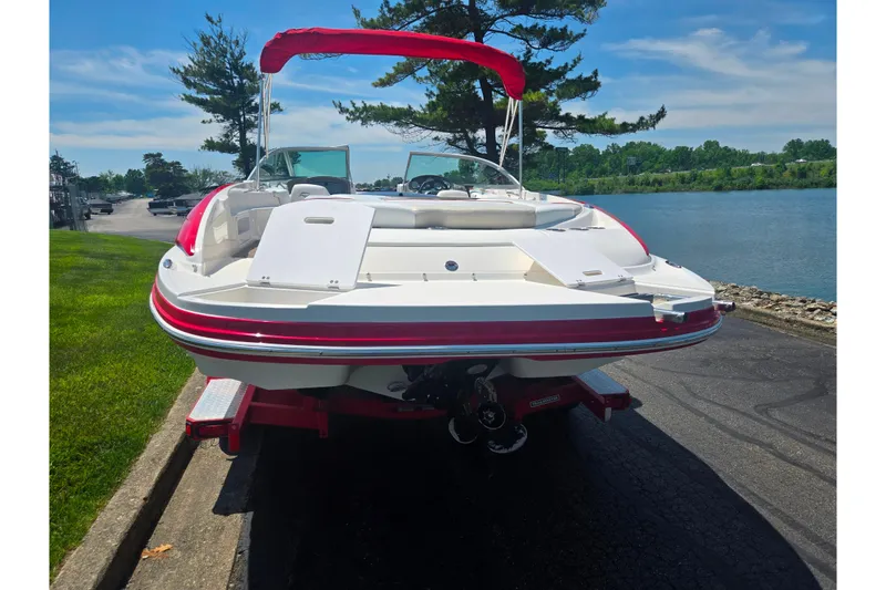 Slide: The Image of 2008 Rinker 226 Captiva Bowrider on trailer by a lakeside, featuring red accents. - 2