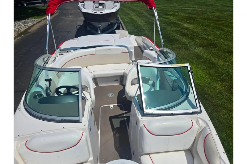 Slide: The Image of 2008 Rinker 226 Captiva Bowrider with red accents, parked on grass. - 21