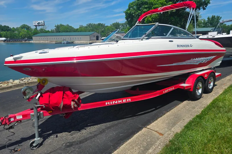 Slide: The Image of 2008 Rinker 226 Captiva Bowrider boat on trailer, red and white design, parked by waterfront. - 8