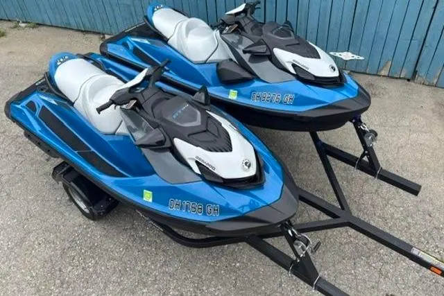 Slide: The Image of Two 2021 Seadoo GTI SE 130 jet skis on trailers, parked on pavement. - 6