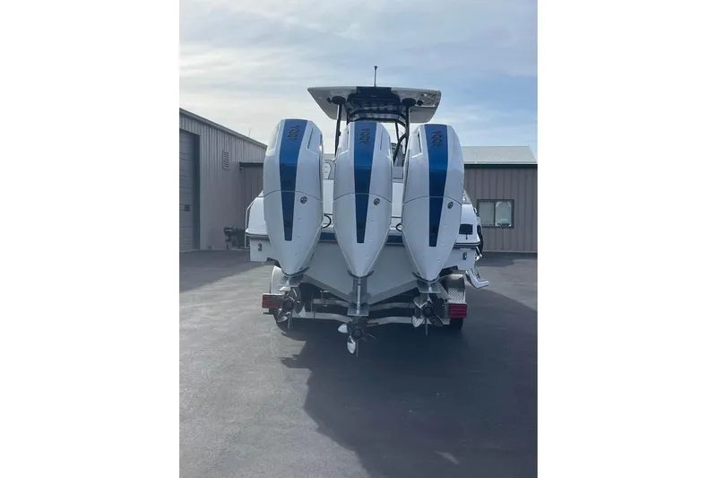 Slide: The Image of 2026 Renegade 38 Open boat with triple outboard engines, parked outdoors. - 16