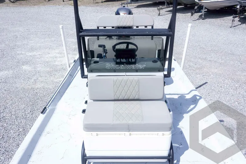 Slide: The Image of 2017 Shoalwater 19' Catamaran with cushioned seating and steering console, parked on gravel. - 16