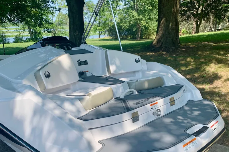 Slide: The Image of 2015 Scarab 165 ID boat with white seating, parked near trees and a lake. - 11