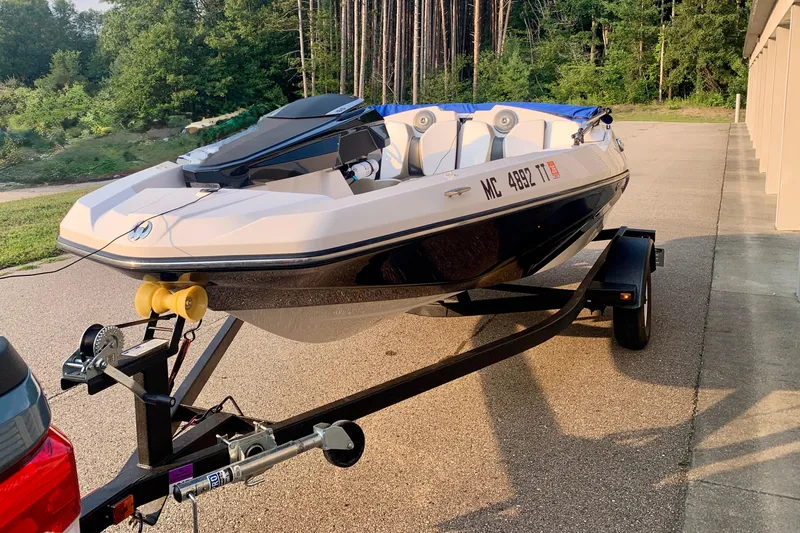 Slide: The Image of 2015 Scarab 165 ID boat on trailer, parked outdoors near forest. - 3