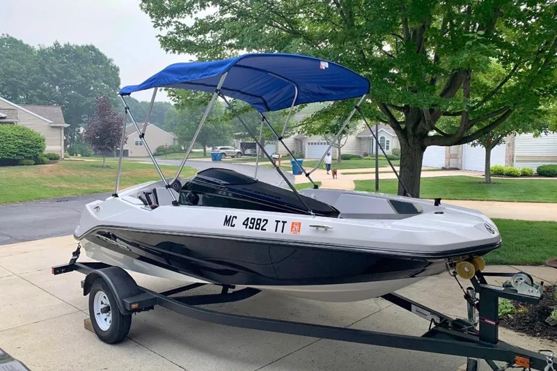 Slide: The Image of 2015 Scarab 165 ID boat with blue canopy on trailer in suburban driveway. - 4