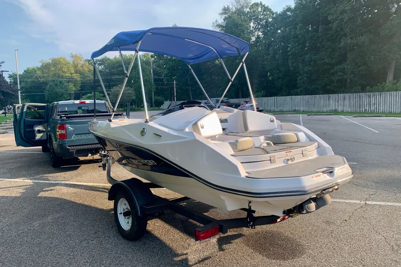 Slide: The Image of 2015 Scarab 165 ID boat on trailer, parked in sunny lot with trees. - 8