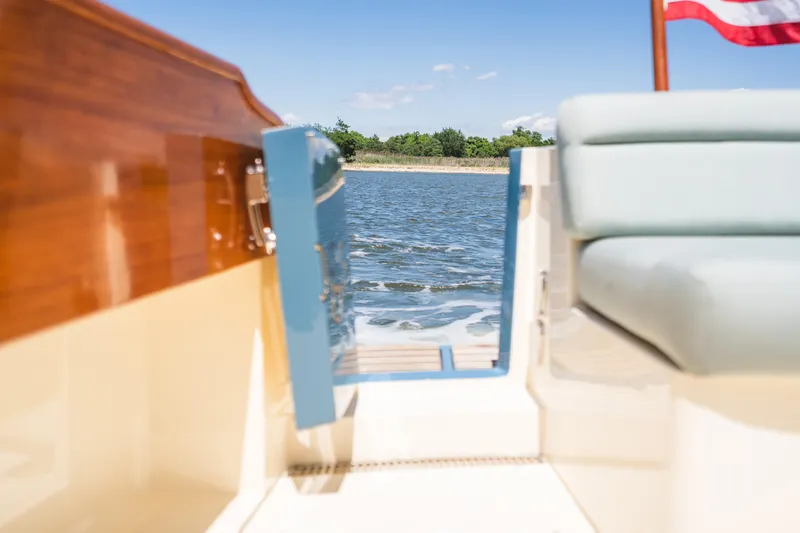 Slide: The Image of Hinckley Talaria 34 yacht interior view, showcasing elegant woodwork and serene water backdrop. - 11