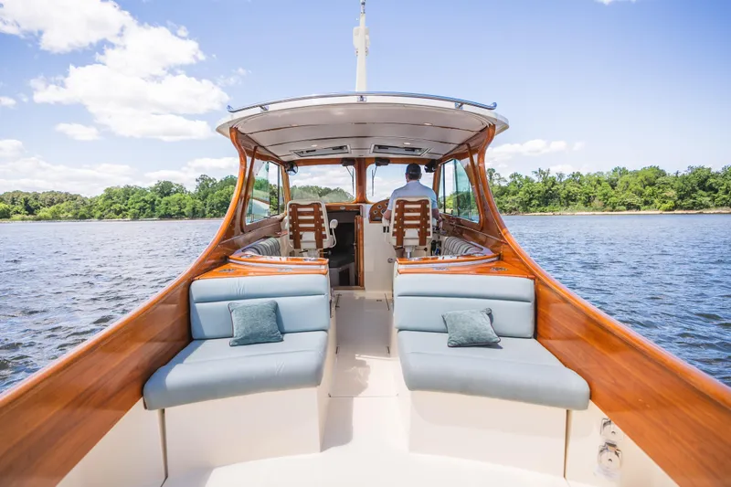 Slide: The Image of 2013 Hinckley Talaria 34 cruising on a scenic lake with plush seating and wooden accents. - 12