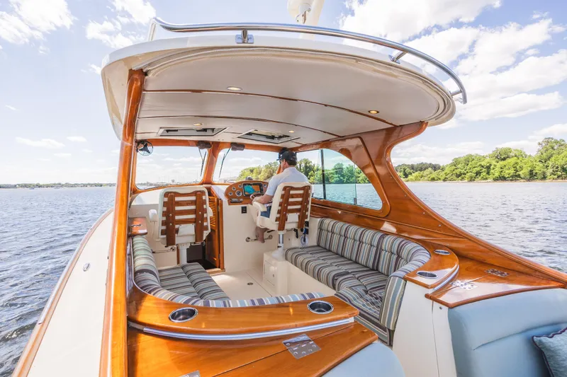 Slide: The Image of 2013 Hinckley Talaria 34 boat interior with wood accents and striped seating on a sunny day. - 16