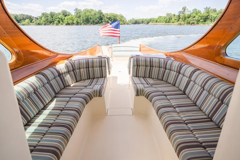 Slide: The Image of Hinckley Talaria 34 boat interior with striped seating, American flag, and scenic water view. - 17