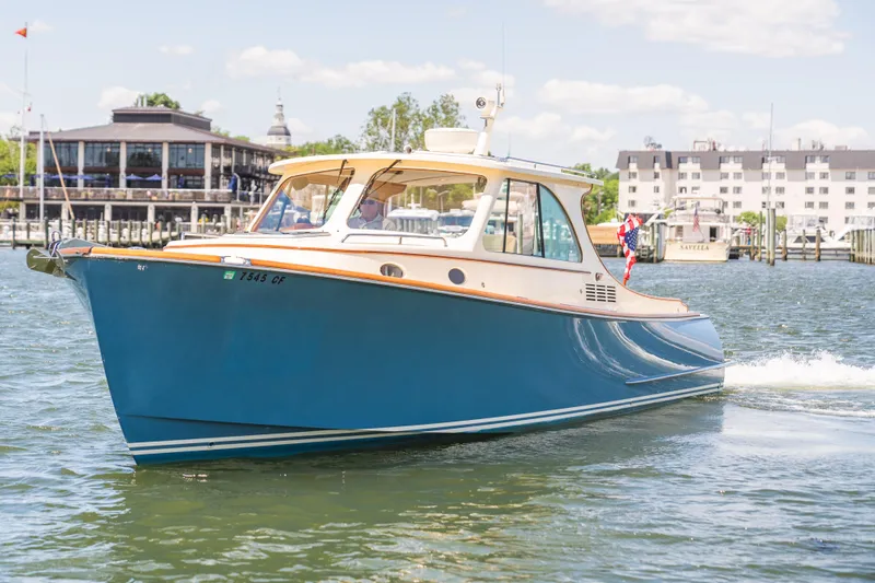 Slide: The Image of 2013 Hinckley Talaria 34 cruising in a marina with buildings in the background. - 2