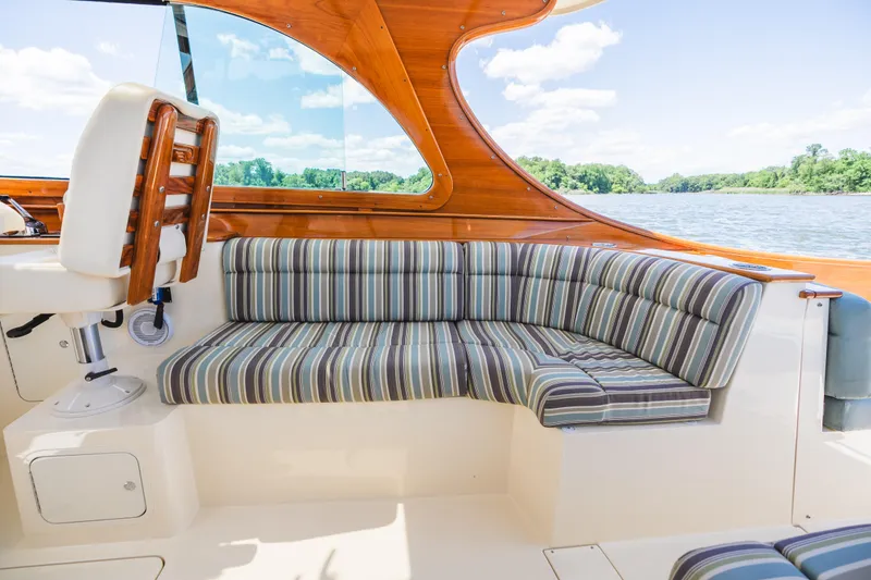 Slide: The Image of 2013 Hinckley Talaria 34 boat interior with striped seating and wooden accents. - 20