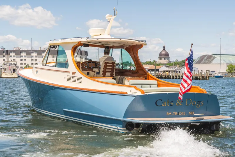 Slide: The Image of 2013 Hinckley Talaria 34 yacht cruising in a harbor, displaying an American flag. - 3