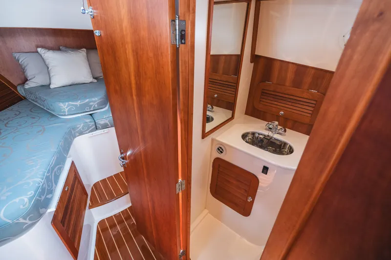 Slide: The Image of Hinckley Talaria 34 interior, featuring a cozy cabin with bed and compact bathroom. - 35