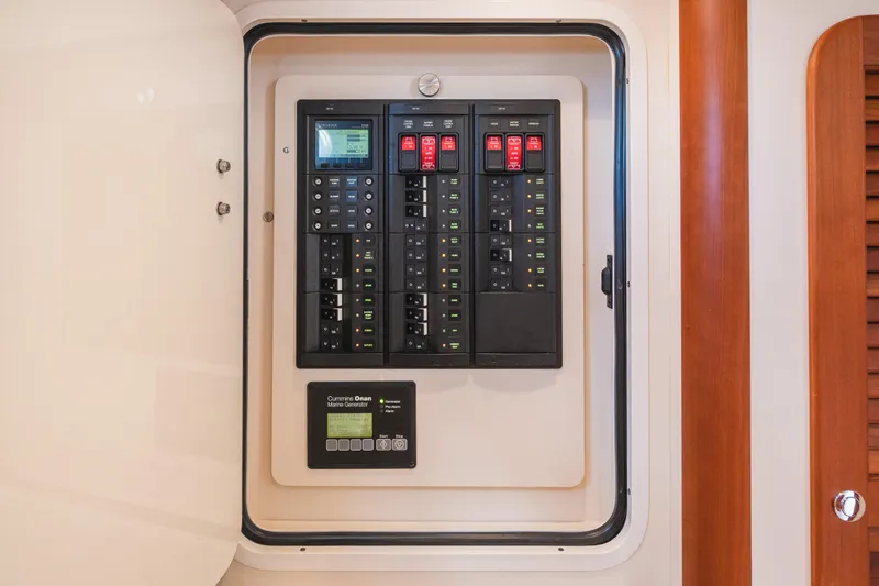 Slide: The Image of Electrical panel inside 2013 Hinckley Talaria 34 yacht, featuring Cummins Onan marine generator controls. - 37