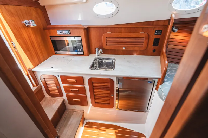 Slide: The Image of Hinckley Talaria 34 yacht interior kitchen with wood cabinetry, sink, microwave, and refrigerator, 2013 model. - 38