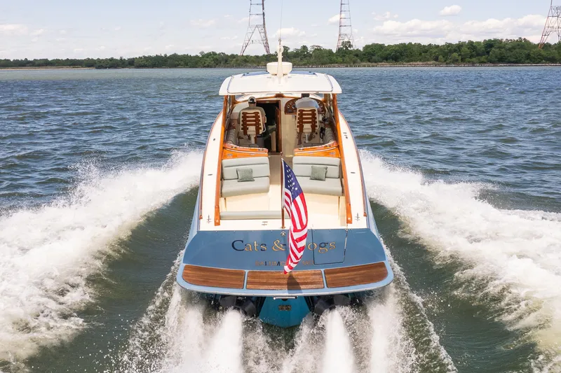 Slide: The Image of 2013 Hinckley Talaria 34 cruising on water, American flag displayed, scenic background. - 4