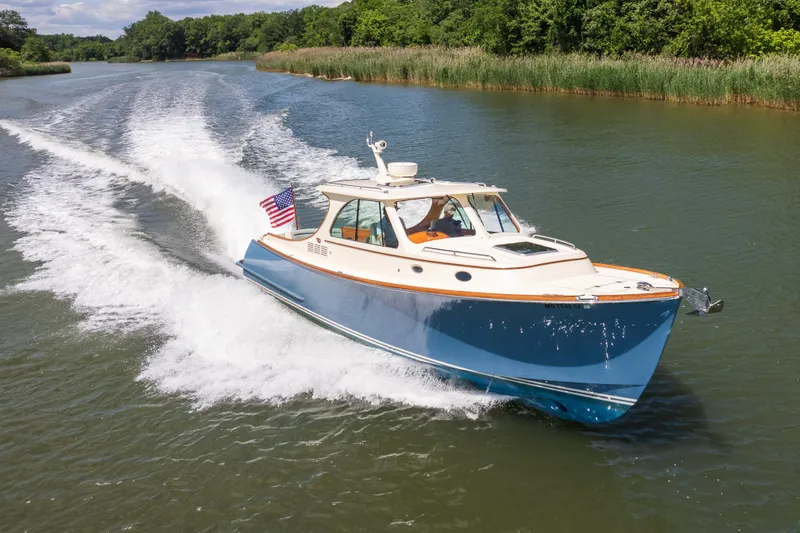 Slide: The Image of 2013 Hinckley Talaria 34 cruising on a scenic river with lush greenery. - 7