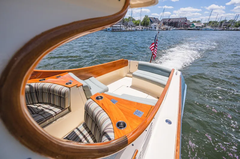 Slide: The Image of 2013 Hinckley Talaria 34 cruising on water, featuring elegant seating and American flag. - 9