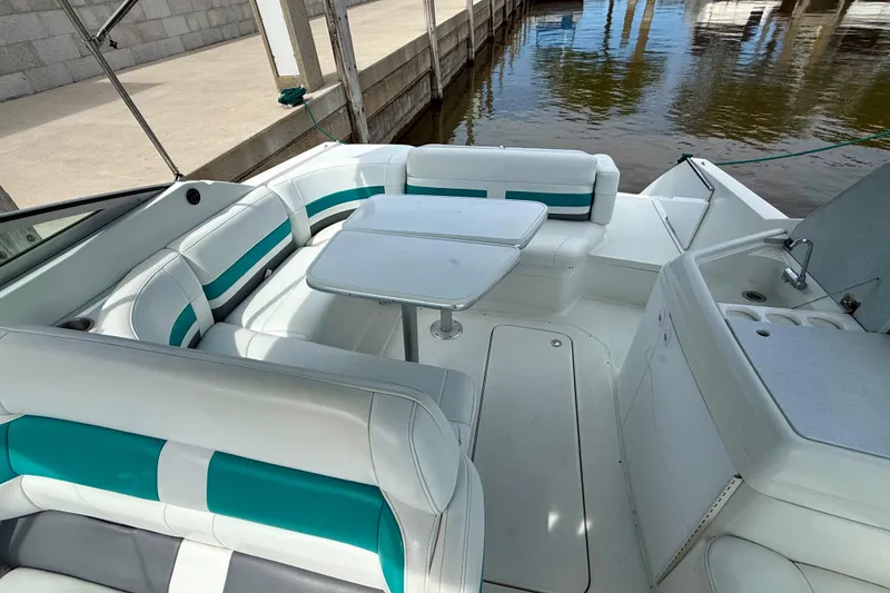 Slide: The Image of 1995 Formula 280 Sun Sport boat interior with white and teal seating, docked by the water. - 11