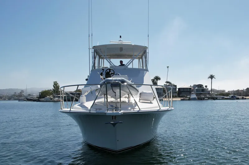 Slide: The Image of 2006 Cabo 40 Flybridge yacht on calm water, with coastal homes in the background. - 9