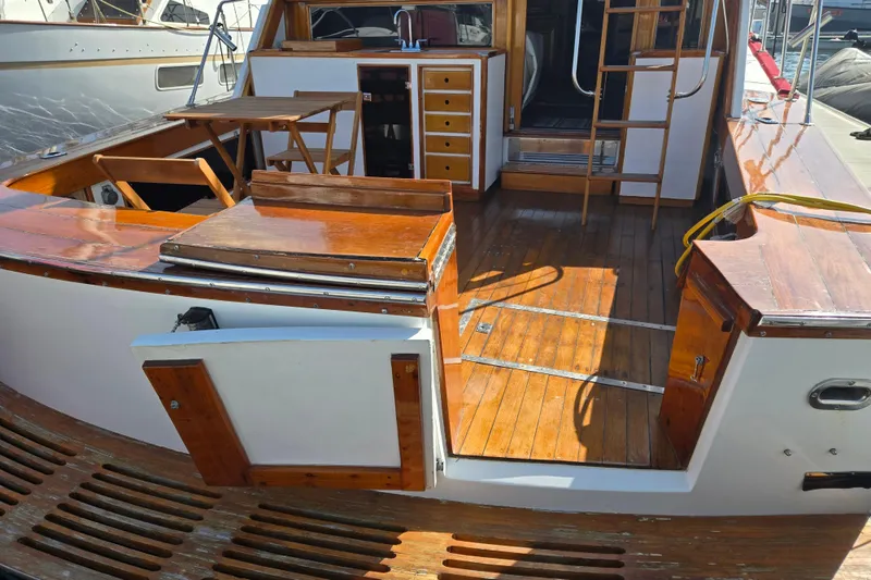 Slide: The Image of 1980 Egg Harbor 52 Convertible yacht deck with chairs and wooden flooring at marina. - 18