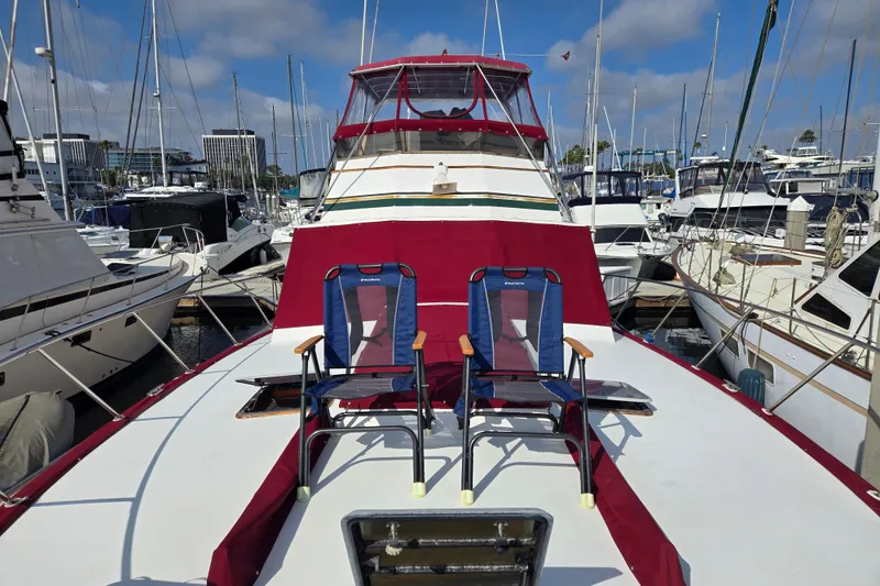 Slide: The Image of 1980 Egg Harbor 52 Convertible yacht docked, featuring wooden deck and seating area. - 36
