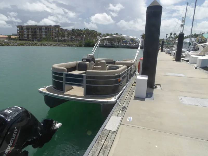 Slide: The Image of 2024 Harris Pontoon boat docked on a sunny day. - 1