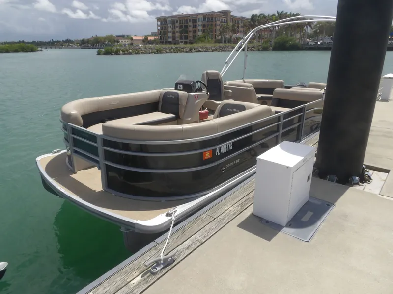 Slide: The Image of 2024 Harris Pontoon boat docked on a sunny day. - 2