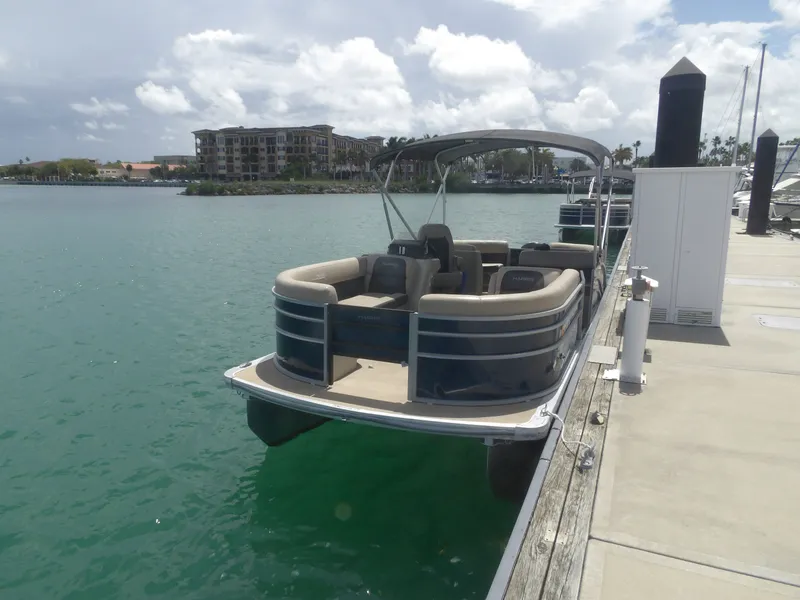 Slide: The Image of 2024 Harris Pontoon boat docked on a sunny day. - 1