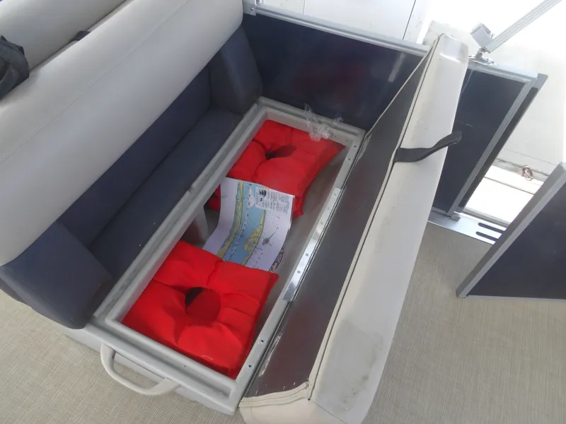 Slide: The Image of 2024 Harris Pontoon seat storage with red life jackets. - 21