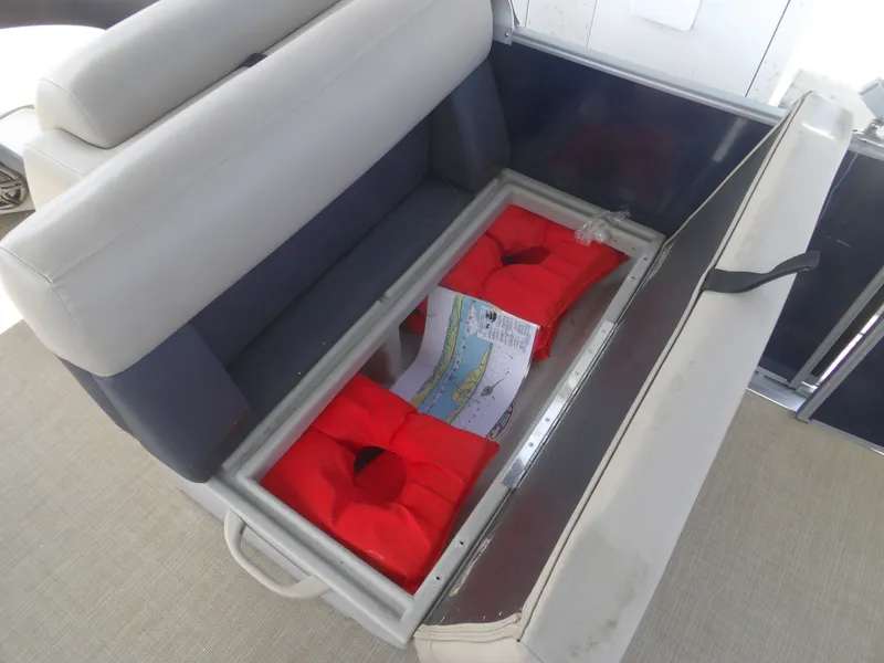 Slide: The Image of 2024 Harris Pontoon seat storage with life jackets and map. - 22