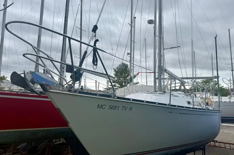 Slide: The Image of 1983 C&C 34 sailboat docked, surrounded by other boats under a cloudy sky. - 2