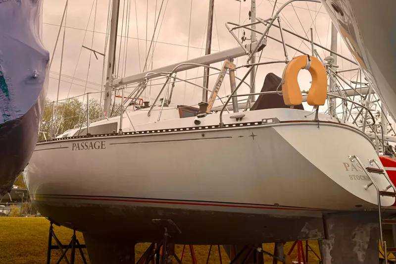 Slide: The Image of 1983 C&C 34 sailboat named "Passage" on dry dock with overcast sky. - 6