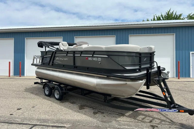 Slide: The Image of 2022 Starcraft CX 21 C pontoon boat on trailer, parked outside blue garage. - 25