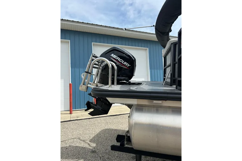 Slide: The Image of 2022 Starcraft CX 21 C boat with Mercury outboard motor, parked near a blue building. - 9