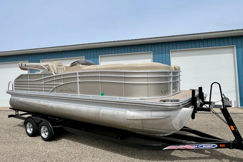 Slide: The Image of 2012 Bennington 2250RCL pontoon boat on trailer, parked outside blue building. - 51