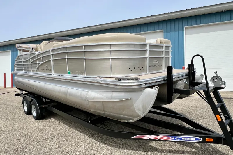 Slide: The Image of 2012 Bennington 2250RCL pontoon boat on trailer, parked outside a blue building. - 53